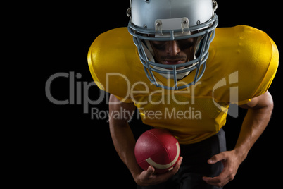 American football player leaning forward holding a ball