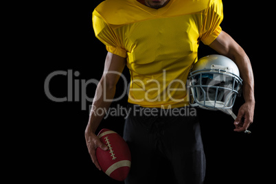 American football player holding a ball and head gear