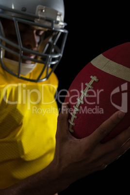 American football player looking at football in his hand