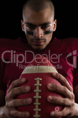 Determined American football player holding a football with both his hands