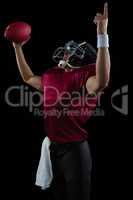 American football player raising hands holding a ball high in one hand