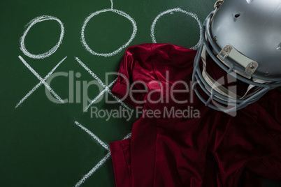 American football jersey and head gear lying on green board with strategy drawn on it