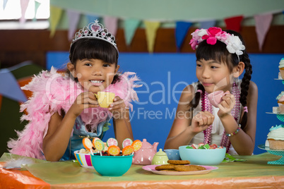 Cute girls having tea at table during birthday party