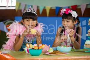 Cute girls having tea at table during birthday party