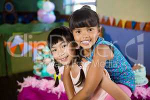 Girl giving piggyback ride to her friend during birthday party