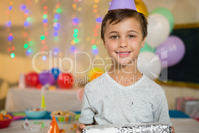 Boy holding a gift box during birthday party at home