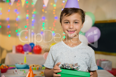 Boy holding a gift box during birthday party at home