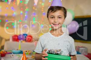 Boy holding a gift box during birthday party at home