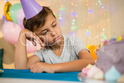 Boy sitting near a birthday cake at home