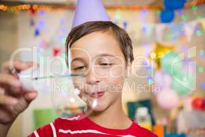Cute boy playing with bubble wand during birthday party