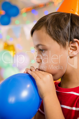 Cute boy blowing balloon during birthday party