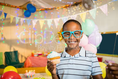 Portrait of cute boy holding cupcake during birthday party Portrait of cute boy holding cupcake during birthday party
