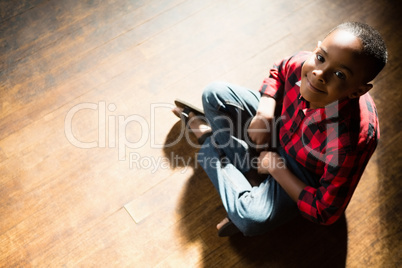 Portrait of happy boy sitting on wooden floor