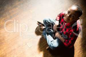 Portrait of happy boy sitting on wooden floor