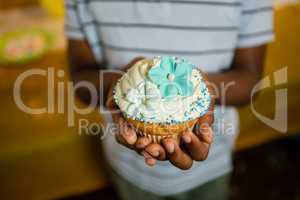 Mid section of boy holding decorated cupcake during birthday