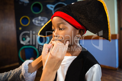 Hand of woman drawing mustache on boy face