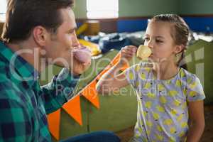 Playful girl and father having tea from the toy kitchen set