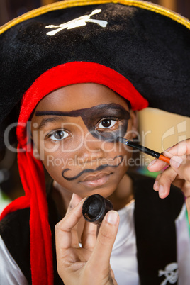 Hand of woman drawing on boy eyes