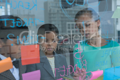 Colleagues discussing while writing on glass