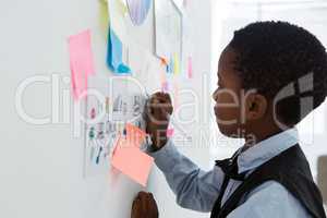 Businessman writing on paper at whiteboard in creative office