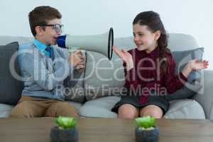 Businesswoman looking at colleague shouting into megaphone