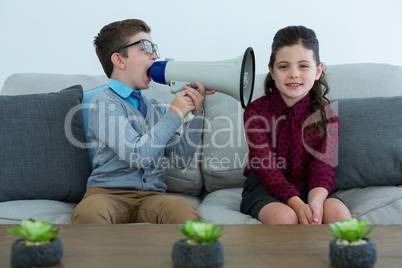 Businessman shouting through megaphone into female colleagues ear