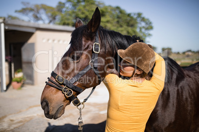 Rear view of female jockey embracing horse