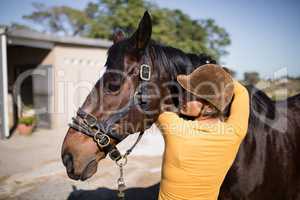 Rear view of female jockey embracing horse