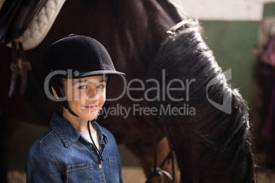 Portrait of girl wearing helmet standing by horse