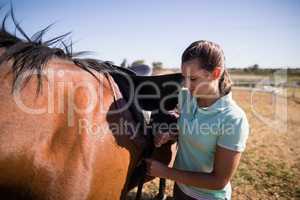 Female jockey fastening saddle