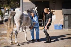 Female jockey talking to vet examining horse hoof