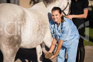 Portrait of female vet examining horse hoof