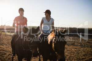 Female friends riding horses against sky