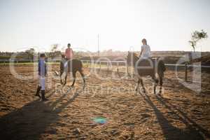 Trainer guiding young women in riding horse