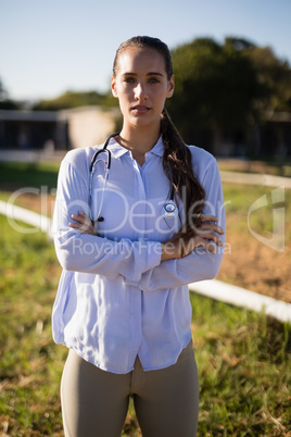 Portrait of female vet with arms crossed standing at barn