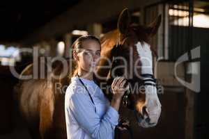 Female vet stroking horse at stable