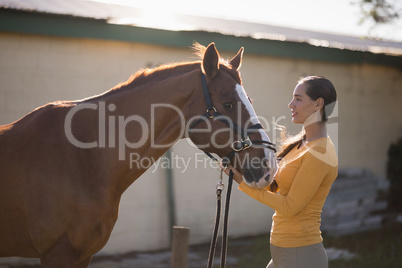 Female jockey with horse at barn