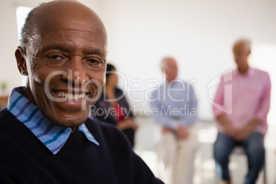 Close up Portrait of smiling senior man with friends in background Close up Portrait of smiling senior man with friends in background