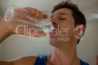 Close up of male athlete drinking water in fitness club