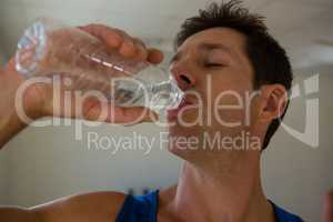 Close up of male athlete drinking water in fitness club