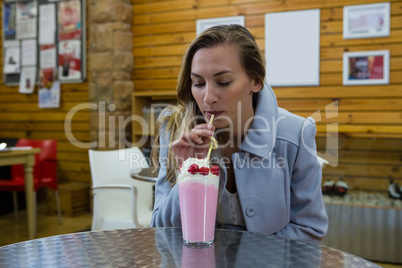 Woman having drink while sitting in cafe
