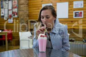 Woman having drink while sitting in cafe