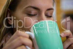 Close up of woman with eyes closed drinking coffee at cafe