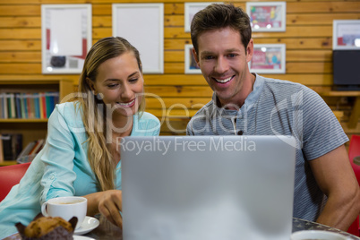 Couple using laptop while sitting in coffee shop