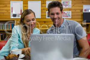 Couple using laptop while sitting in coffee shop