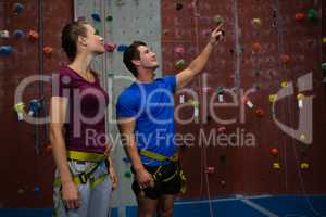 trainer guiding athlete in climbing wall at gym