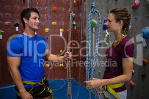 Trainer training female athlete in climbing wall at club
