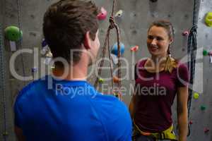 Trainer guiding athlete in wall climbing at gym