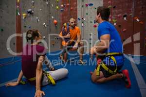 Trainer guiding athletes in wall climbing at gym