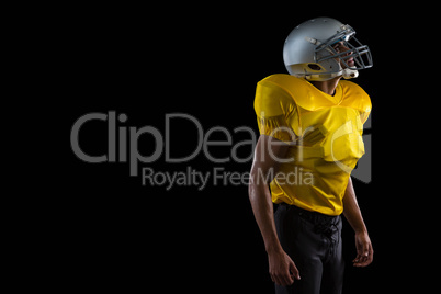 American football player standing against a black background